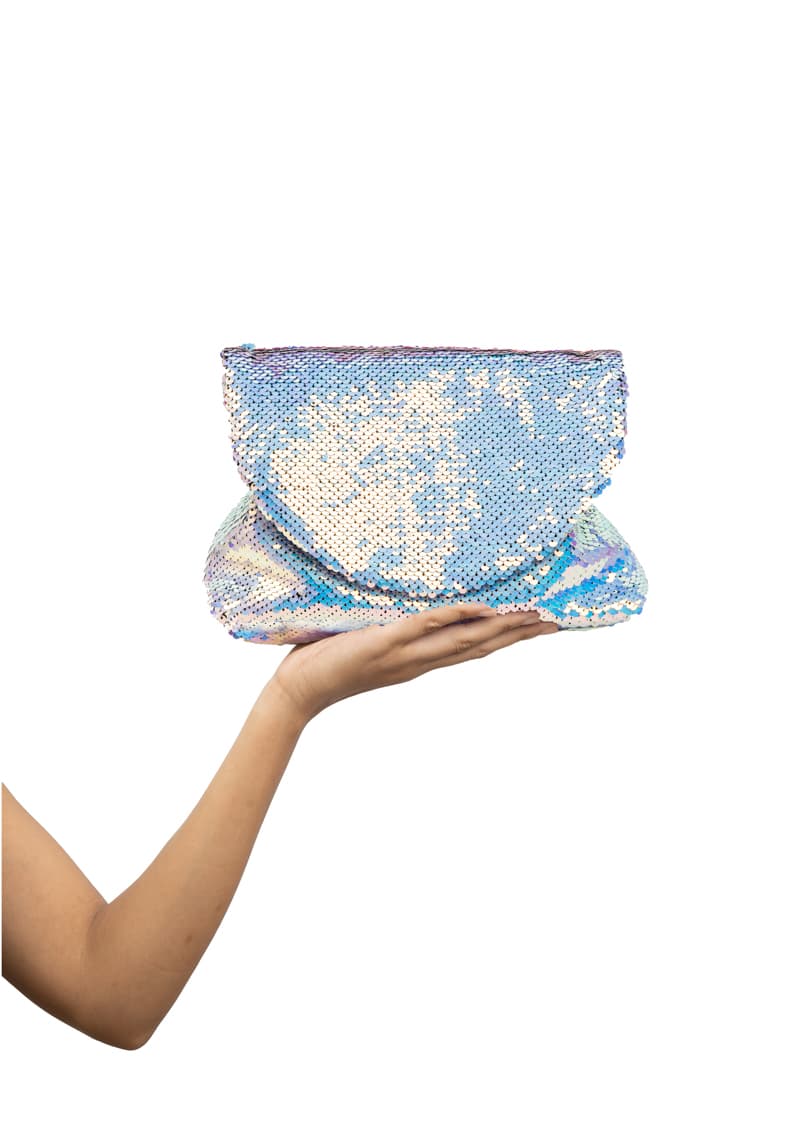 Hand holding a silver sequin clutch against a white background