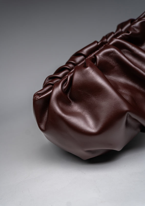 Brown leather handbag on a gray background